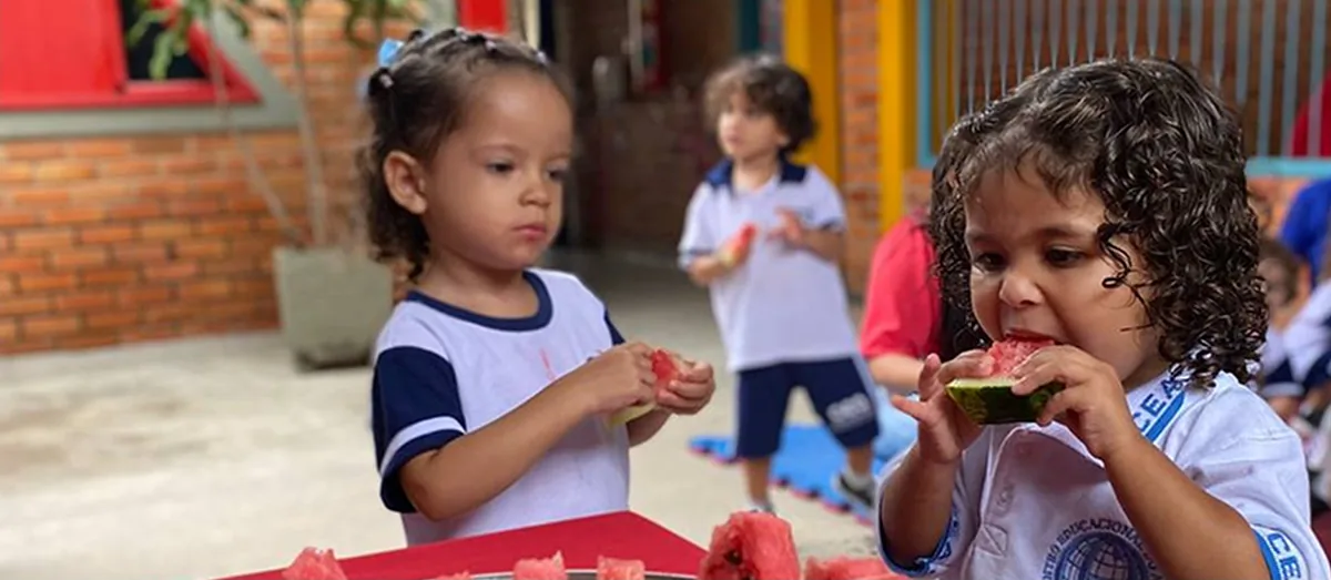 Crianças comendo melancia no pátio da escola