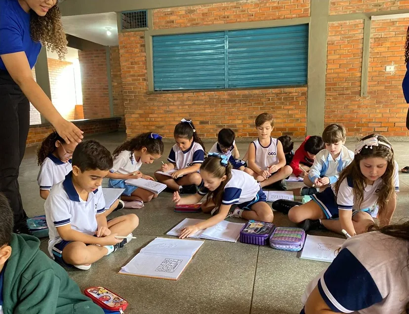 Crianças fazendo uma atividade sentadas no chão da sala