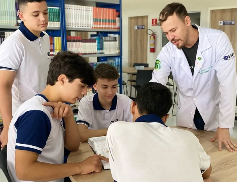 Professor orientando alunos do Ensino Médio na biblioteca